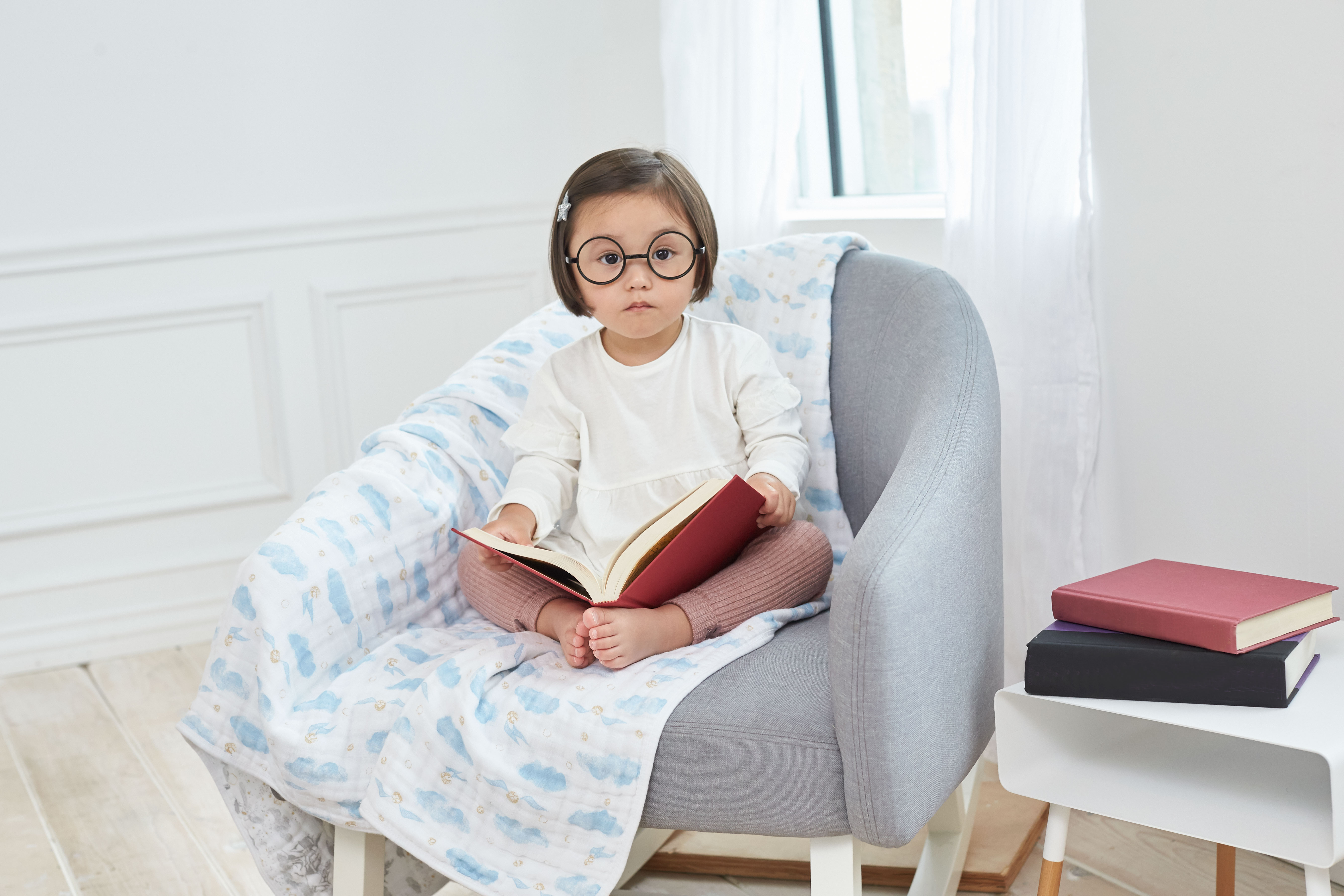 Baby in round glasses with a book